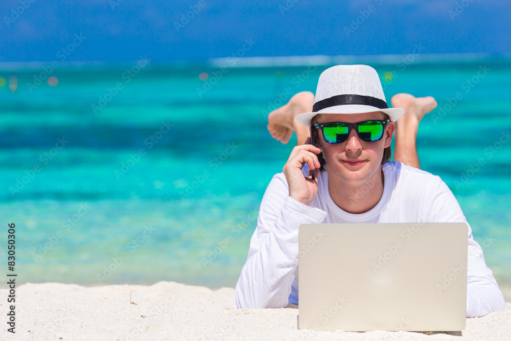 Young man with tablet computer and cell phone on tropical beach