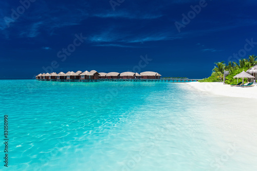 Overwater bungallows in blue lagoon on tropical island