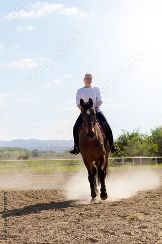 Beautiful blonde woman riding a horse in countryside