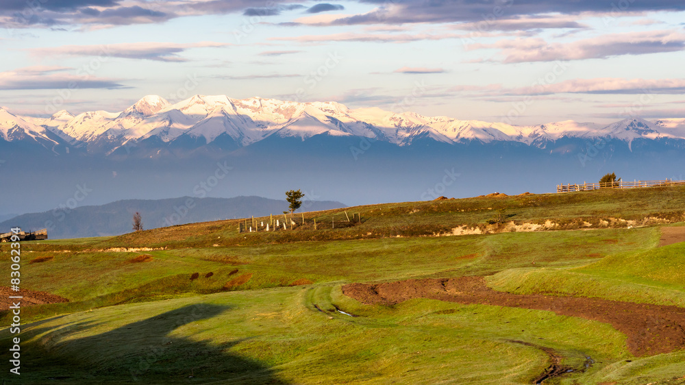 Obraz premium Rural scene and high snowy mountain on a background.