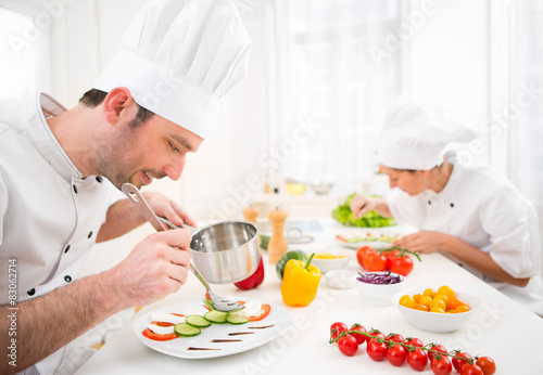 Young attractive professional chef cooking in his kitchen