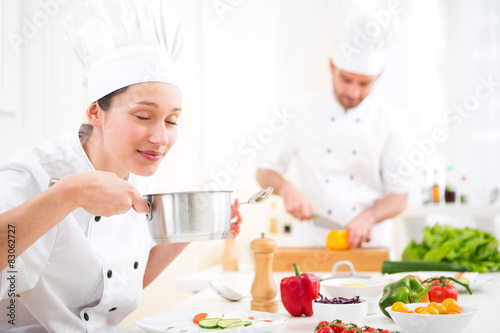 Young attractive professional chef tasting sauce