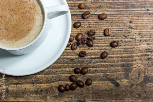 Cup of coffee amid whole coffee beans