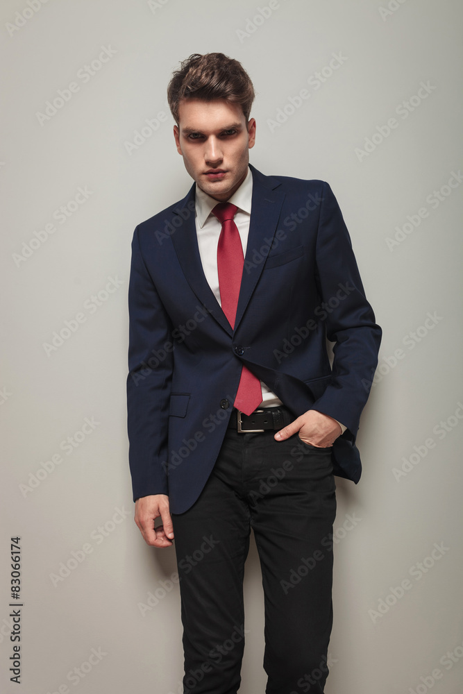 Fototapeta premium Young handsome business man leaning on a grey wall