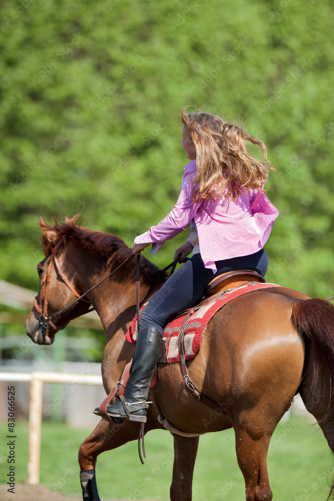 girl riding her brown horse in a training field