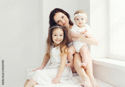Portrait of mother with two daughters in white room near window © rohappy