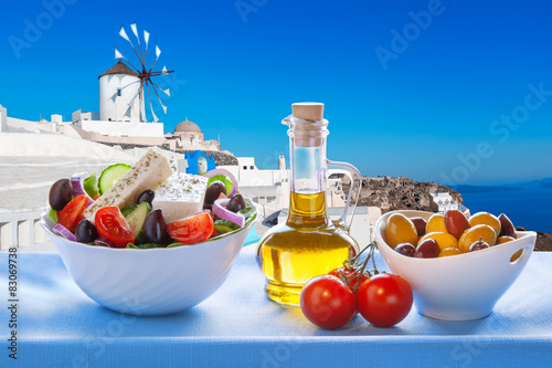 Greek salad against windmill in Santorini island, Greece