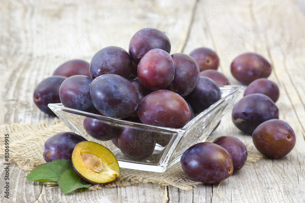Fototapeta premium fresh plums in a bowl on old wooden background