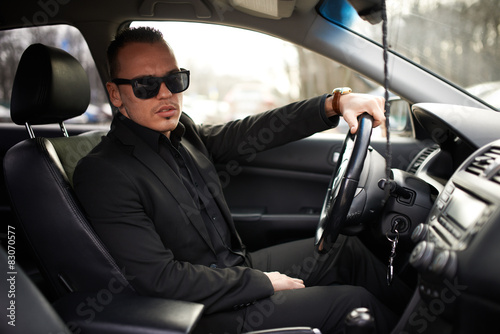 man in black suit sitting behind the wheel