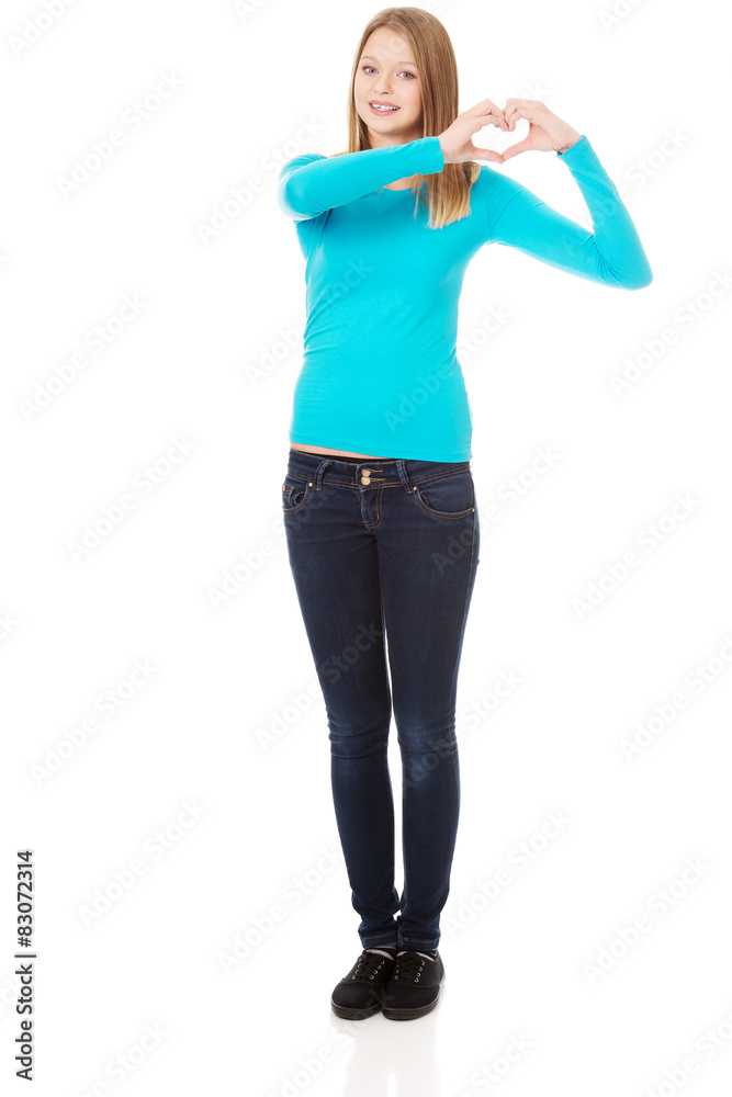 Fototapeta premium Smiling teenage woman making heart shape