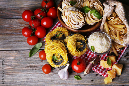 Pasta with cherry tomatoes and other ingredients on wooden table background