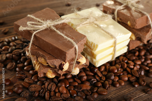 Stack of tied chocolate with coffee beans on wooden table, closeup