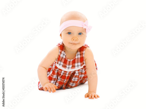 Portrait of little baby girl in the dress crawls on a white back
