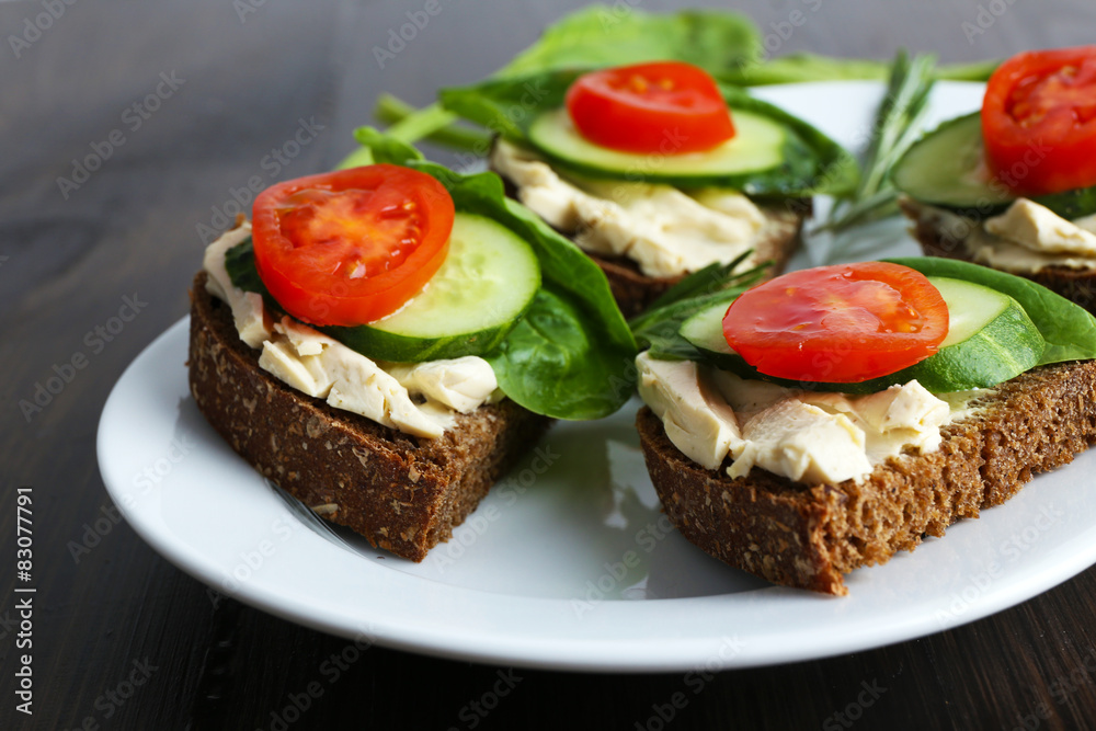 Delicious sandwiches with vegetables and greens on plate close up