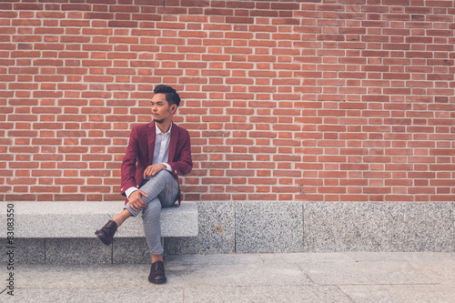 Handsome Asian model sitting in the city streets