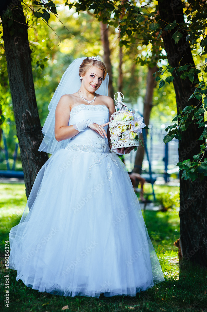 Beautiful bride posing outdoor at the park in her wedding day
