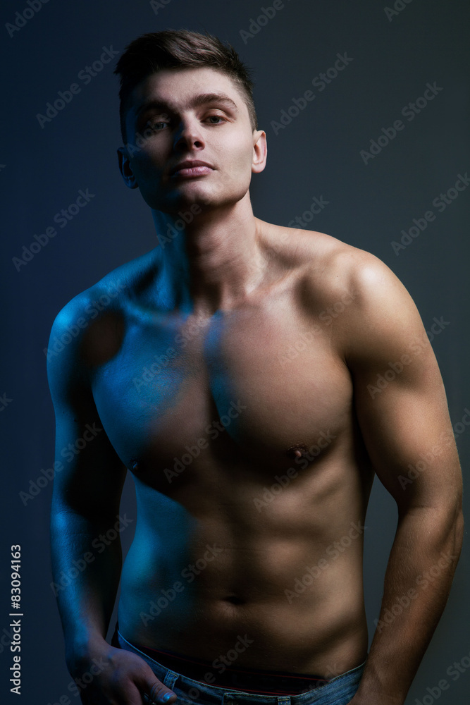 Handsome sexy young man with muscular body in jeans looking at c