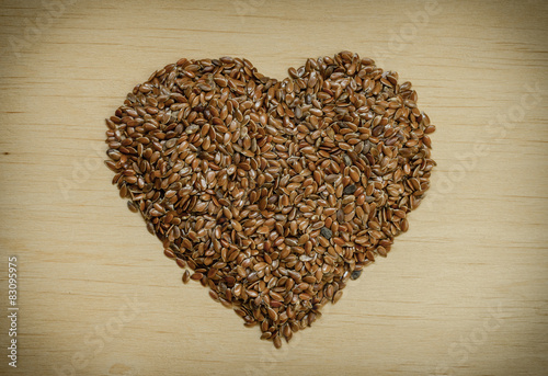Raw flax seeds linseed heart shaped on wooden table © Voyagerix