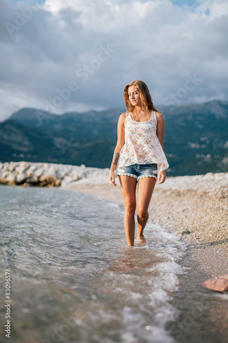 dreamy fashion girl walk on beach with mountains background