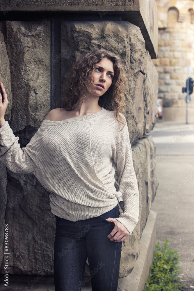 Naklejka premium Outdoors portrait of a beautiful girl in sweater and jeans