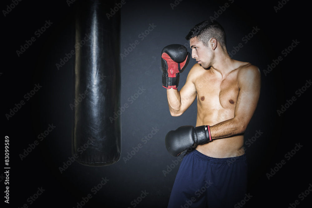 Muscular man training with punching bag at gym
