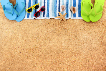 Sunglasses on a summer beach sand background top border with couple sunbathing towel and accessories photo space for copy text