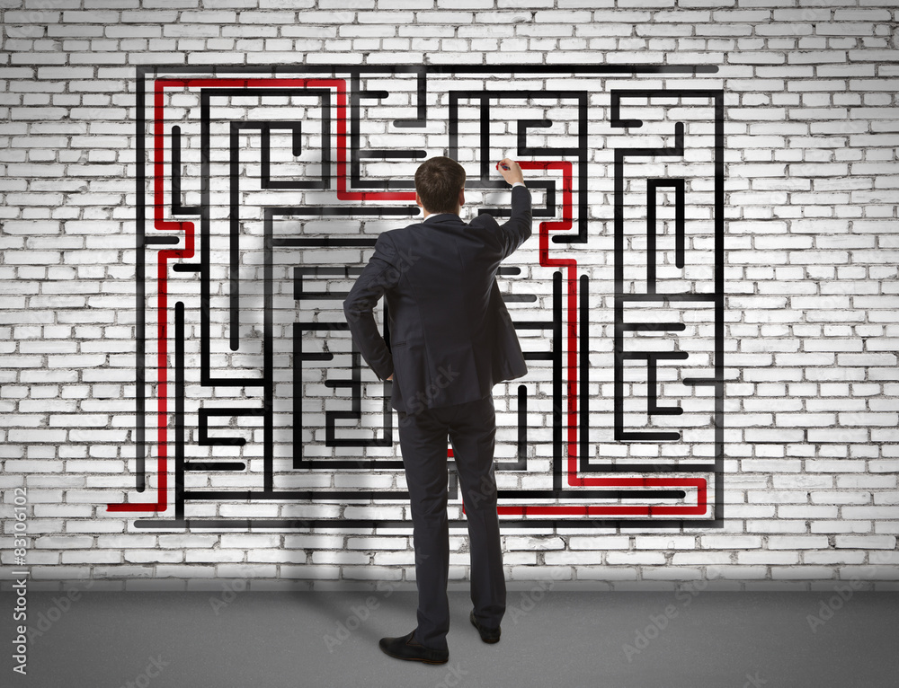 Businessman drawing labyrinth on wall Businessman drawing labyrinth on wall