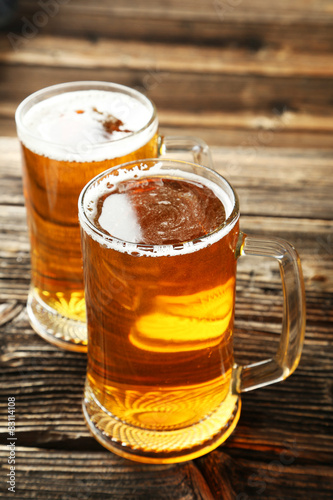 Two mug of beer on brown wooden background