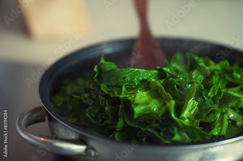 Vegetarian food concept. Fresh spinach cooking in metal pot. 