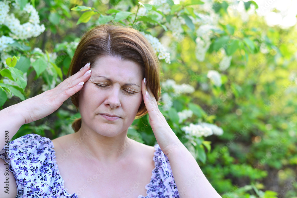 adult woman with  headache about bird cherry blossoms in spring