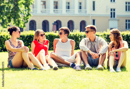 group of smiling friends outdoors sitting on grass