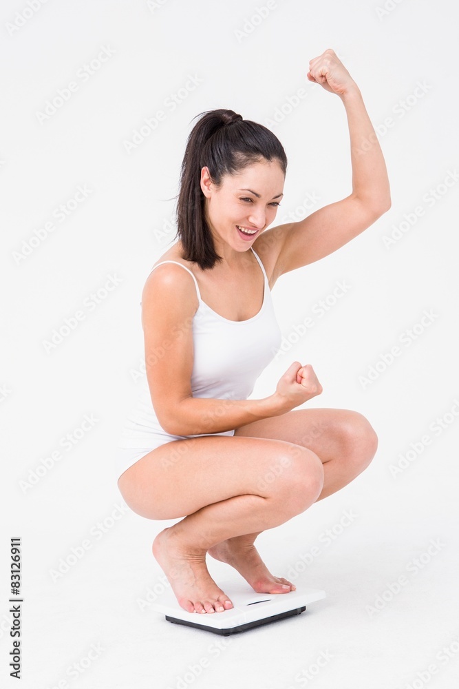 Beautiful woman cheering on weighing scales Beautiful woman cheering on weighing scales