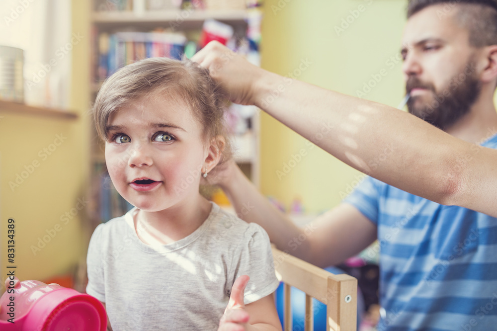 Fototapeta premium Young father styling hair of his daughter