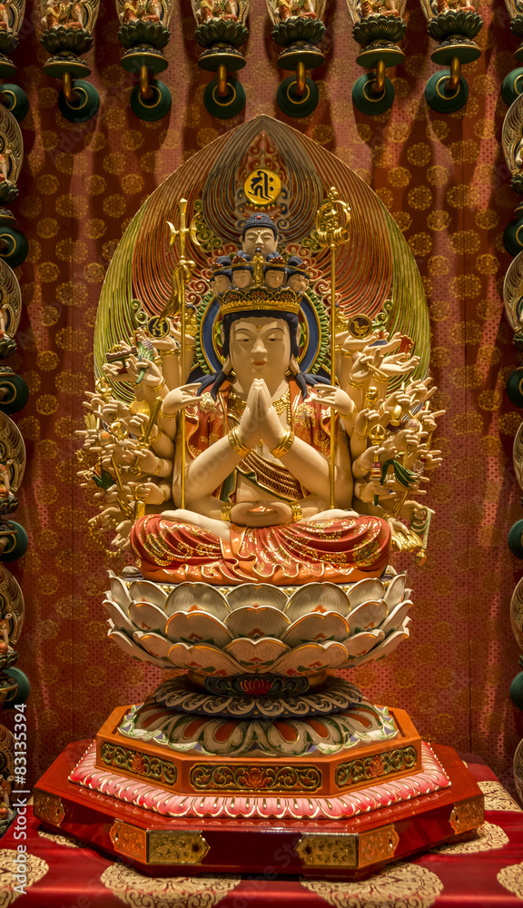 small statue of Buddha with many arms, in a Buddhist temple