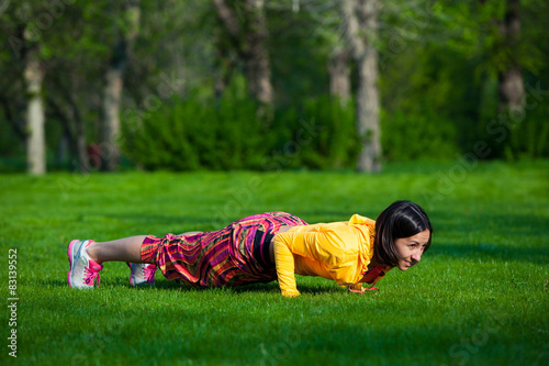 press ups exercise by young woman. Girl working out on grass