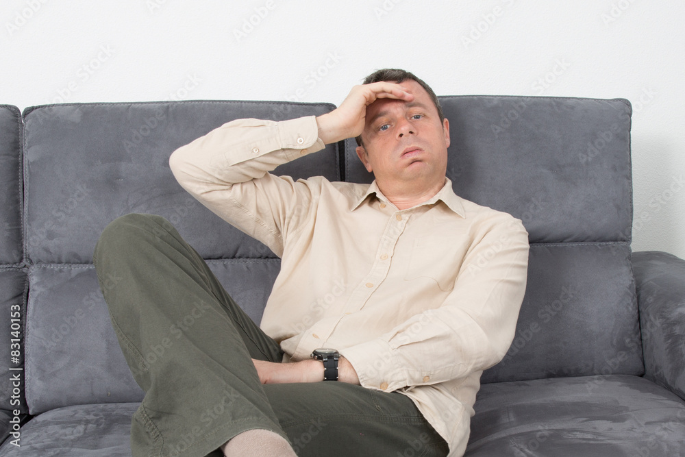 Portrait of a upset man sitting on sofa in house Portrait of a upset man sitting on sofa in house