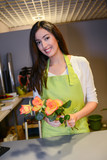 cheerful young woman florist selling flowers in flower shop