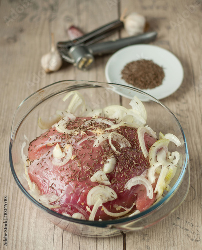 raw pork meat in roaster with onion cumin and garlic on wooden t photo