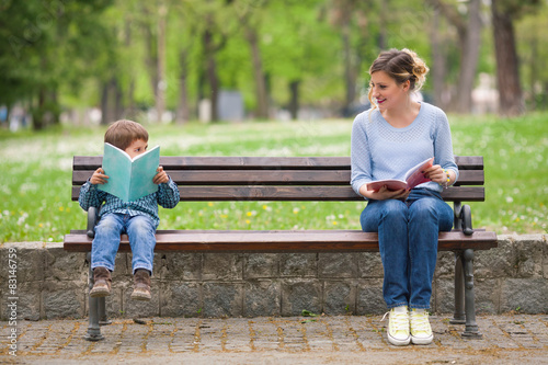 Young woman and cute little boy reading books 