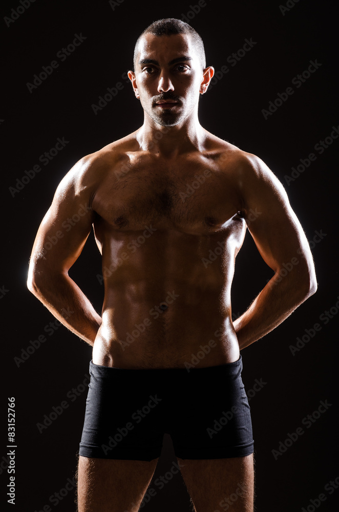 Fototapeta premium Muscular man posing in dark studio