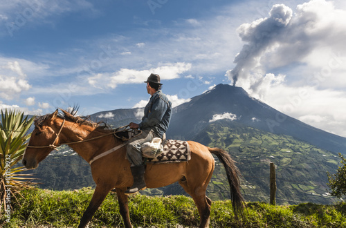 Unrecognizable farmer on a horse front of volcano Tungurahua photo