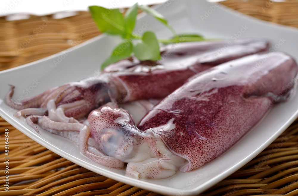 fresh whole round squid on plate with rattan background fresh whole round squid on plate with rattan background