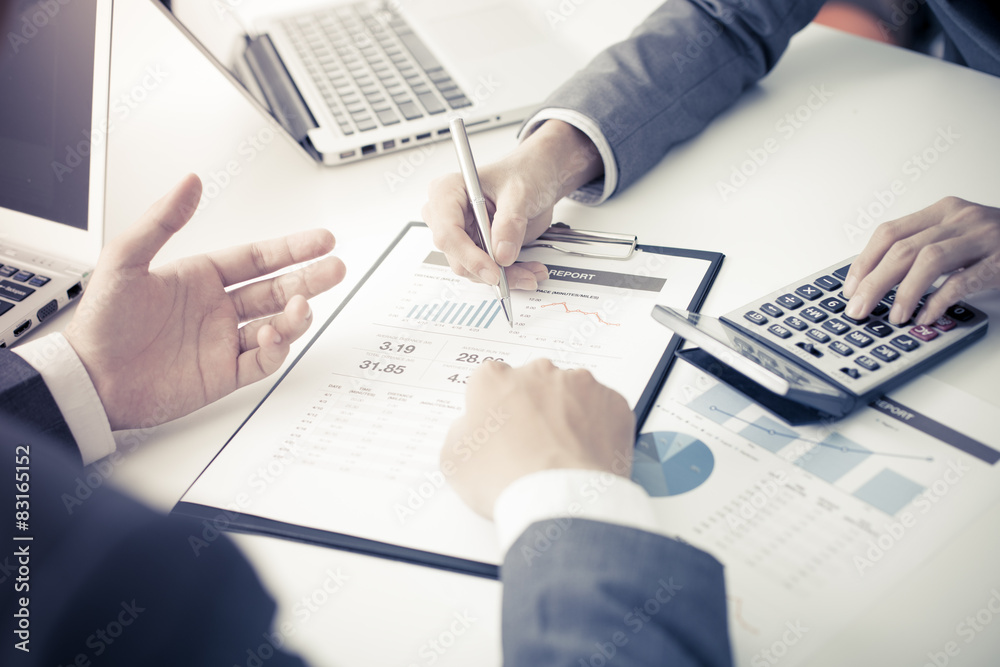 Two businessmen looking at report and having a discussion in off Two businessmen looking at report and having a discussion in off