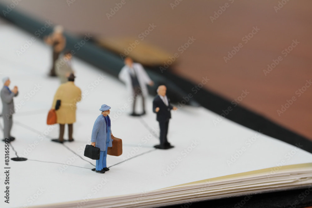 close up of miniature people with social network diagram on open close up of miniature people with social network diagram on open