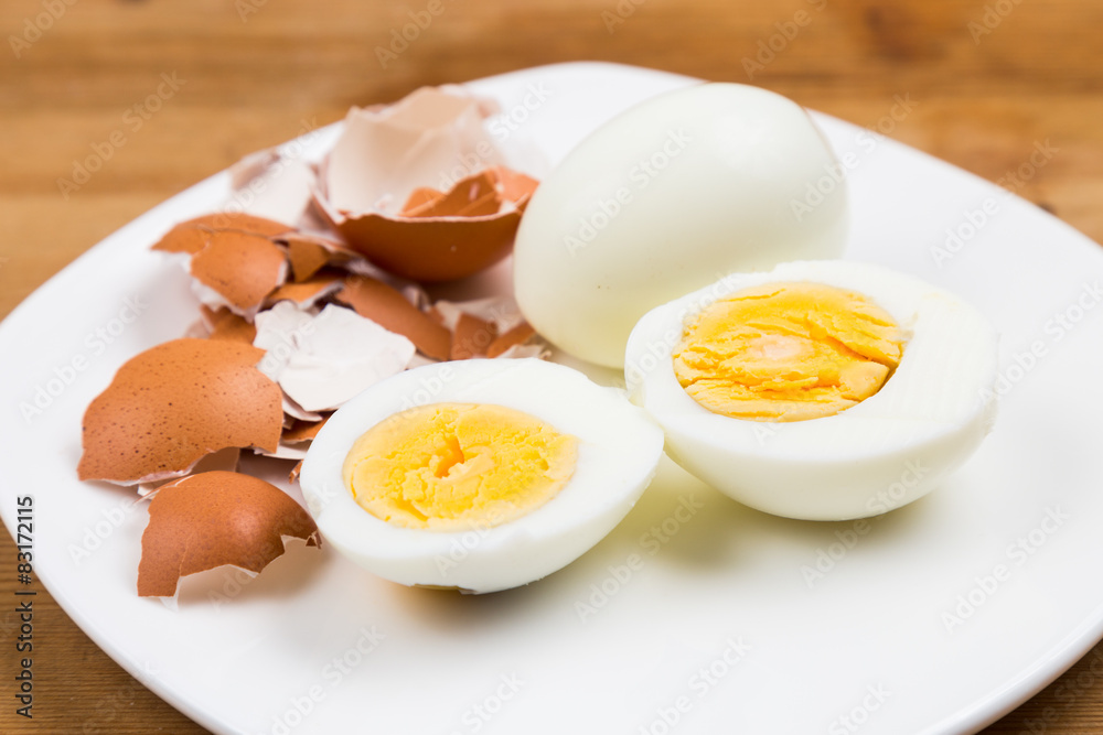 Hard boiled egg with peeled and shattered shells on plate Hard boiled egg with peeled and shattered shells on plate