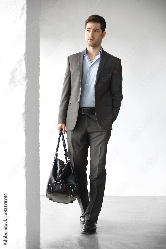 Podróż biznesowa. Przystojny mężczyzna w garniturze z walizką
 - obrazy, fototapety, plakaty 