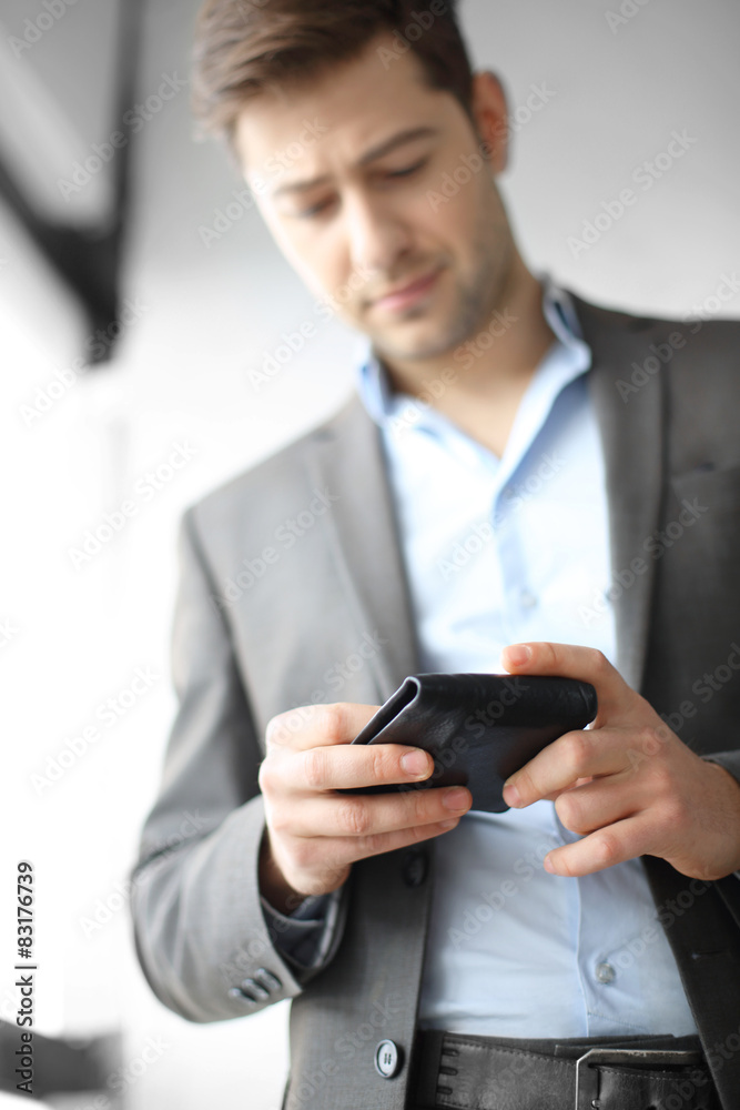 Mężczyzna w garniturze trzyma w dłoni portfel - obrazy, fototapety, plakaty 