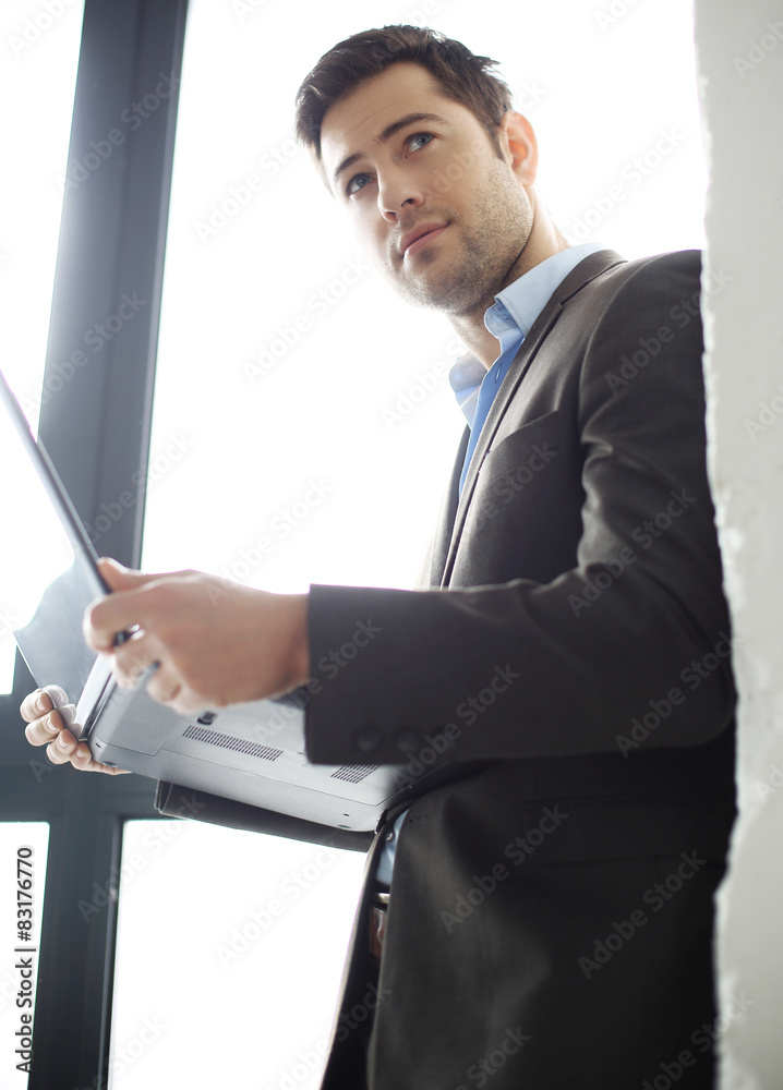Biznesmann. Mężczyzna w garniturze pracuje z komputerem - obrazy, fototapety, plakaty 