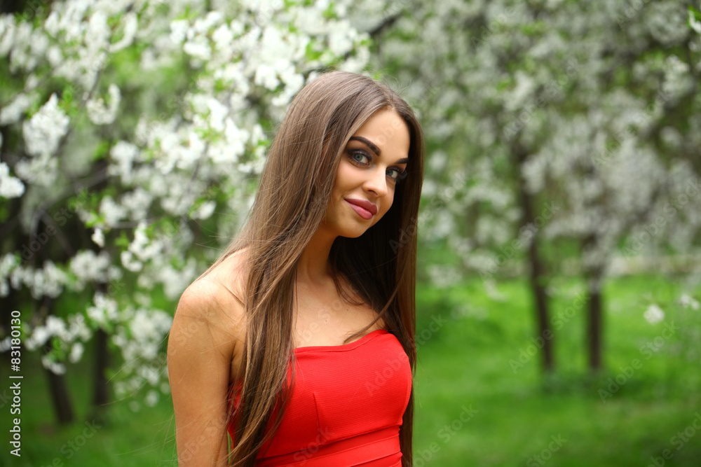 Happy young woman in red dress against the background spring flo Happy young woman in red dress against the background spring flo