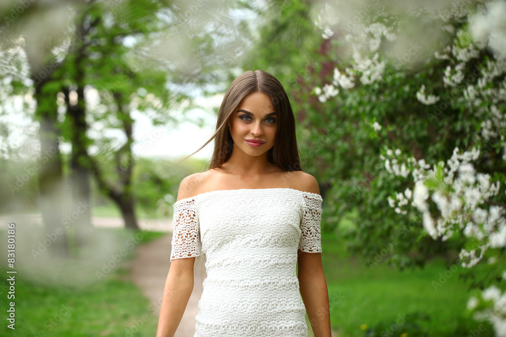 Happy young woman in white dress against the background spring f